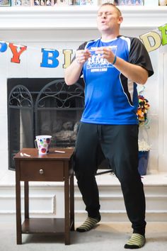 a man standing in front of a fire place next to a table with cups on it