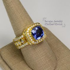 This 18k solid gold Vintage Ring has a eye catching blue sapphire as its center piece. The sapphire ring has a very unique band set with diamonds and multiple layers of diamonds.This ring has a GIA certificate.Ring Size: 8.75Total Weight: 18.53 gramsPrecious Metal: 18k solid goldPrecious stones:-Blue Sapphire heat only Center Stone: 4 carats, 11mm x 10.3mm-White Round and Square Diamonds: 1.38 carats Yellow Gold Tanzanite Diamond Ring With Halo Setting, Yellow Gold Tanzanite Diamond Ring With Accent Stones, Gold Tanzanite Diamond Ring Fine Jewelry, Sapphire Ring In Yellow Gold With Halo Setting, Luxury Tanzanite Jewelry With Center Stone, Heirloom Sapphire Ring With Diamond Gemstone Accents, Fine Jewelry Sapphire Ring With Diamond And Gemstone Accents, Gold Tanzanite Ring With Halo Setting, Luxury Sapphire Jewelry With Halo Setting