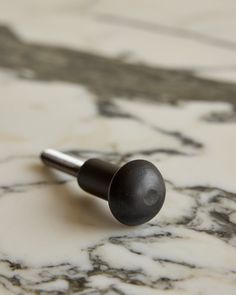 a pair of black screws sitting on top of a marble countertop next to a metal object