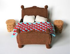 a crocheted bed with pillows and blankets on it is shown in front of a white wall