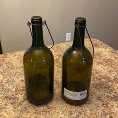 two green glass bottles sitting on top of a counter