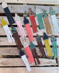 a bunch of different colored leather tassels hanging on a wooden pallet