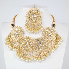 Unveil your elegance this festive season with our Deepika Kundan Choker Set—a stunning embodiment of Indian tradition infused with a modern edge. This magnificent set, meticulously crafted by skilled artisans, is an ode to the timeless beauty of kundan jewelry. The choker, embellished with intricate kundan work and delicate pearls, rests gracefully on a base of gleaming gold plating, making it an ideal companion for sarees, lehengas, or any festive attire. Paired with matching earrings and a str Festive Jewelry With Stone Work For Celebration, Elegant Kundan Necklace For Navratri Festivities, Eid Party Jewelry With Cutdana, Festive Eid Temple Jewelry Sets, Bollywood Style Festive Necklace With Gota Work, Festive Chandbali Bridal Sets For Eid, Eid Celebration Chandbali Jewelry Sets, Elegant Kundan Necklace With Gota Work For Festivals, Elegant Kundan Jewelry Set For Navratri