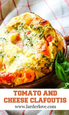 an omelet with tomatoes, cheese and spinach in it on a red and white checkered cloth