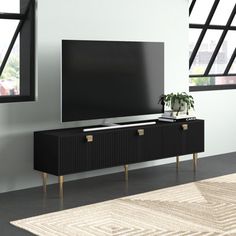 a black entertainment center with two drawers and a plant on it in front of a large window