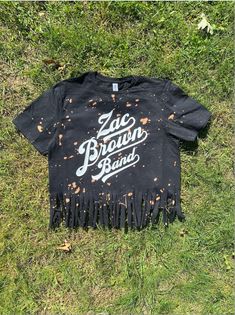 a black t - shirt that says zac brown band on it laying in the grass