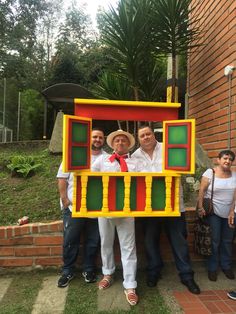 three men standing in front of a house made out of legos and fake windows