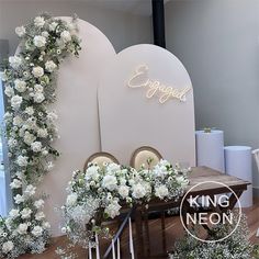 white flowers and greenery on display in front of a sign that says engaged, king neon