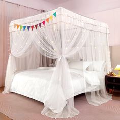 a white bed with sheer curtains and lights on it