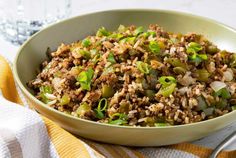 a bowl filled with meat and vegetables on top of a yellow towel next to a fork