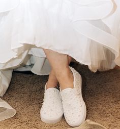 a woman in white shoes is sitting on the floor with her wedding dress flowing down