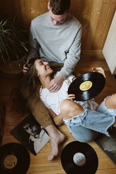 a man and woman sitting on the floor next to records