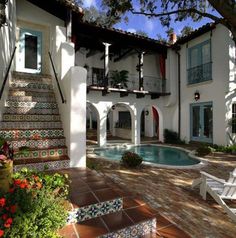 a house with a pool in the front yard and stairs leading up to it's second story