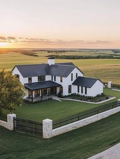 an aerial view of a large white house in the middle of a green field at sunset