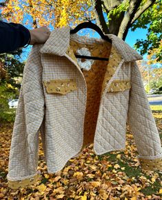 a jacket hanging from a tree with leaves on the ground