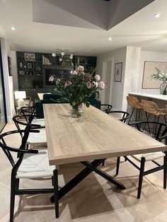 a dining room table with chairs and flowers in a vase on the centerpieces