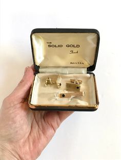 "A unique set of cuff links and a tie clip that comes in what appears to be the original box. Though the box says \"the solid gold touch,\" I do not see a gold stamp on any of the pieces. There is a patent pending stamp on the tie clip, however. These might be gold plate? I'm not sure. CONDITION: The box shows considerable wear on the inside, with fraying to the satin. The jewelry pieces themselves are in great condition for their age. Have a question? Please ask me anything." Vintage Rectangular Cufflinks For Gifts, Classic Jewelry Gift For Father's Day, Classic Jewelry Gift Box For Father's Day, Gold Cuff Links, Touch Gift, Gold Touch, Black Gems, Gold Cufflinks, Gold Cuffs