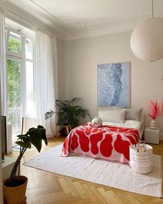 a bedroom with white walls and wooden floors has a large painting on the wall above the bed