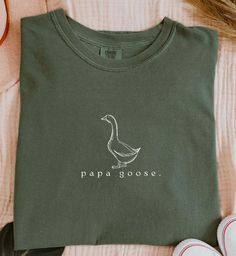 Papa Goose Shirt Silly Goose Shirt for Dad Tshirt Goose Family Shirt for Silly Goose Birthday Party Dad Shirt Goose Tee Matching Family This Comfort Colors shirt  features a simplistic graphic of a vintage-style drawing of a goose and the text "papa goose." below. Available in bay, blue jean, white, denim, moss, and mustard. Please note that the ink color on the white, mustard, and bay is black. Find the baby shirt here: https://withawildflowerllc.etsy.com/listing/1726137892 Find the youth tee h Casual Tops With Funny Print For Father's Day, Cute Father's Day Shirt With Crew Neck, Father's Day Crew Neck Top With Funny Print, Funny Print Cotton Top For Father's Day, Cute Crew Neck Shirt For Father's Day, Father's Day Funny Print Crew Neck Top, Casual Cotton Tops For Birthday, Cute Cotton Shirt For Father's Day, Cotton Top With Funny Text For Birthday