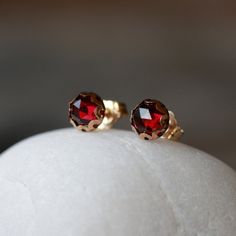 Rich, deep red Garnet gems in a gorgeous rose cut are enveloped in a 14k gold filled scalloped setting in these pretty stud earrings. The posts and wingnut backs are also 14k gold filled--making these earrings perfect for those with sensitive skin and metal allergies. A rose cut gemstone has a series of carved facets leading to an apex at the top, for lots of sparkle. The scalloped setting really enhances the beauty of the gem. The gems measure 6mm, and the earrings themselves are just a little Red Faceted 14k Gold Jewelry, Red Faceted Earrings For Formal Occasions, Victorian Diamond Cut Earrings For Gift, Classic Red Faceted Jewelry, Red Gemstone Earrings In 14k Gold, Red Round Cut Birthstone Earrings, Dainty Red 14k Gold Earrings, Elegant Red Birthstone Earrings, Red Faceted Earrings For Anniversary