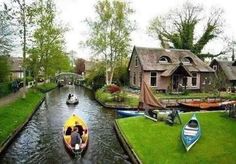 two boats are traveling down the river in front of houses