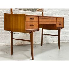 a wooden desk with a mirror on top of it next to a white brick wall