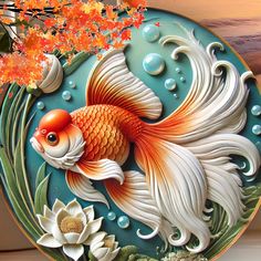 a decorative plate with a goldfish and flowers painted on the side, sitting on a table