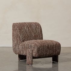 a brown chair sitting on top of a floor next to a white wall and cement floor