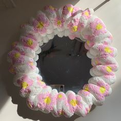 there is a pink and yellow flowered wreath on the wall in front of a mirror