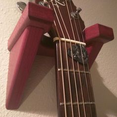 a wooden guitar hanging from the side of a wall with strings attached to it's neck