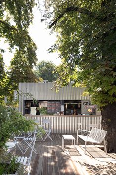 an outdoor deck with chairs and tables under trees