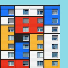 multicolored apartment building with windows and balconies on the side against a blue background