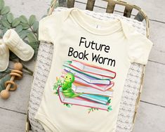 a baby bodysuit that says, future book worm on it next to some books