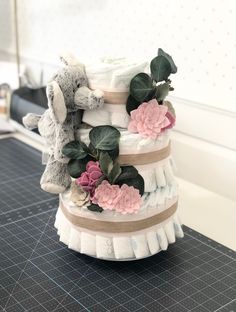 a stack of diapers with stuffed animals and flowers on them sitting on a table