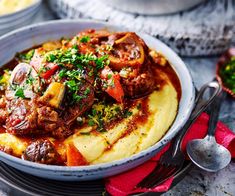 a bowl filled with meat and vegetables on top of mashed potatoes, garnished with parsley