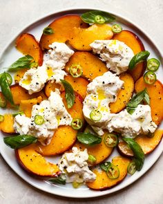 a white plate topped with sliced peaches covered in whipped cream and green peppers on top