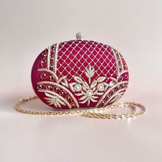 A timeless and classic piece, handcrafted with detailed embroidery and pearl beads. The maroon tones and gold threaded embroidery adds a luxurious feel to the bag and brings the statement factor to your look. With one main compartment and a magnetic fastening, this grande clutch is completed with a chain strap which can be worn as a shoulder bag or tucked in for a clutch style. Elegant Embellished Embroidered Fabric, Elegant Festive Pearl Embroidered Fabric, Elegant Hand-embellished Embroidered Fabric For Festive, Elegant Embellished Embroidered Fabric For Festive Season, Elegant Hand Embellished Embroidered Fabric For Festive, Elegant Hand Embellished Embroidered Fabric For Festive Season, Elegant Formal Embroidered Fabric With Intricate Embroidery, Luxury Embroidered Festive Bag, Red Embroidered Party Bag