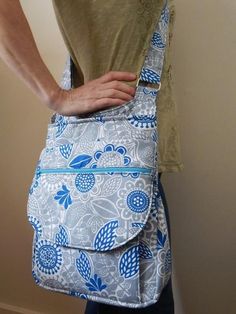 a woman's hand is holding onto a blue and white floral print tote bag