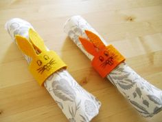 two napkins wrapped in yellow and orange paper with writing on them sitting on a wooden table