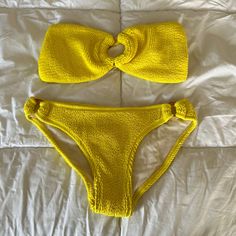 two yellow bikinisuits laying on top of a white bed next to each other