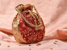 Red Potli Bag with Pearl Handle Strap An ideal for brides rocking the classic red bridal lehenga on their wedding with its classy zari work and a pearl handle strap all in gold the Dulhan Potli Bag is ready to beautify you. Fabric Raw Silk Color Red Embroidery Zari Work in Gold Size amp Dimensions Height - 8 inWidth - 7.5 inDepth - 1.5 in Strap Pearl Handle Strap Closure Tasseled Drawstring Compartments Single compartment Care Wipe with a soft clean amp dry cloth to remove dust When not in use s Red Handwork Potli Bag For Party, Elegant Red Embroidered Potli Bag, Elegant Embroidered Red Potli Bag, Red Festive Pouch, Red Zari Work Potli Bag For Party, Traditional Zari Work Pouch For Party, Bohemian Gold Potli Bag For Wedding, Bohemian Gold Potli Bag For Festive Season, Traditional Party Potli Pouch Bag