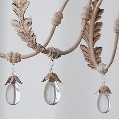 a chandelier hanging from a tree branch with leaves and acrylic tears