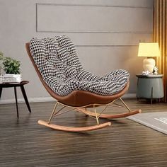 a rocking chair in a living room with wood flooring and white walls, next to a lamp