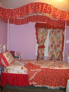 a bed with red bedspread and floral curtains