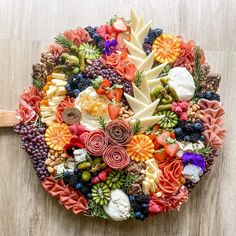 an arrangement of fruits and vegetables is arranged in the shape of a circle on a wooden surface