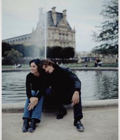 two people sitting on the ground next to a fountain