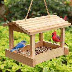 two birds sitting on top of a wooden bird feeder