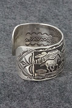 This sterling silver bracelet featuring horses grazing in a Southwestern landscape was made by Navajo silversmith Jeremy Delgarito. The back is signed J Delgarito and stamped sterling.Size: 5 3/8" (will fit up to a 6 3/4" wrist)Gap: 1 3/8"Width: 1 1/4"Free shipping on all orders! We ship with USPS and always include tracking. All orders ship within a day of payment.Returns are accepted up to 30 days after you receive your order. Just send us a message. Our shop offers cash back or store credit. Handmade Western Sterling Silver Bracelet For Gift, Western Sterling Silver Cuff Bracelet Gift, Western Sterling Silver Bracelets With Concho, Western Sterling Silver Concho Bracelets, Western Sterling Silver Adjustable Bracelet Stamped 925, Western Sterling Silver Cuff Bracelet, Southwestern Etched Bracelets For Collectors, Western Sterling Silver Bracelets, Western Style Engraved Sterling Silver Jewelry