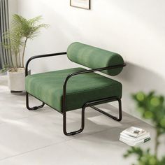 a green chair sitting on top of a white floor next to a potted plant