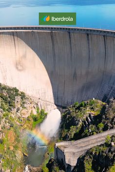 an aerial view of a large dam with a rainbow in the middle